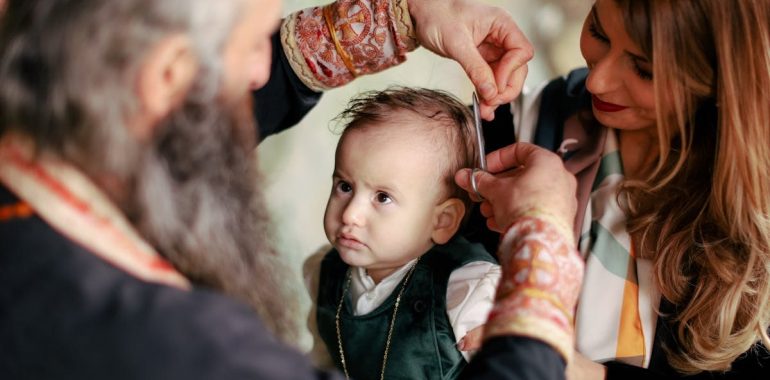 A baby's first haircut performed during a religious ritual with parents and clergy present.